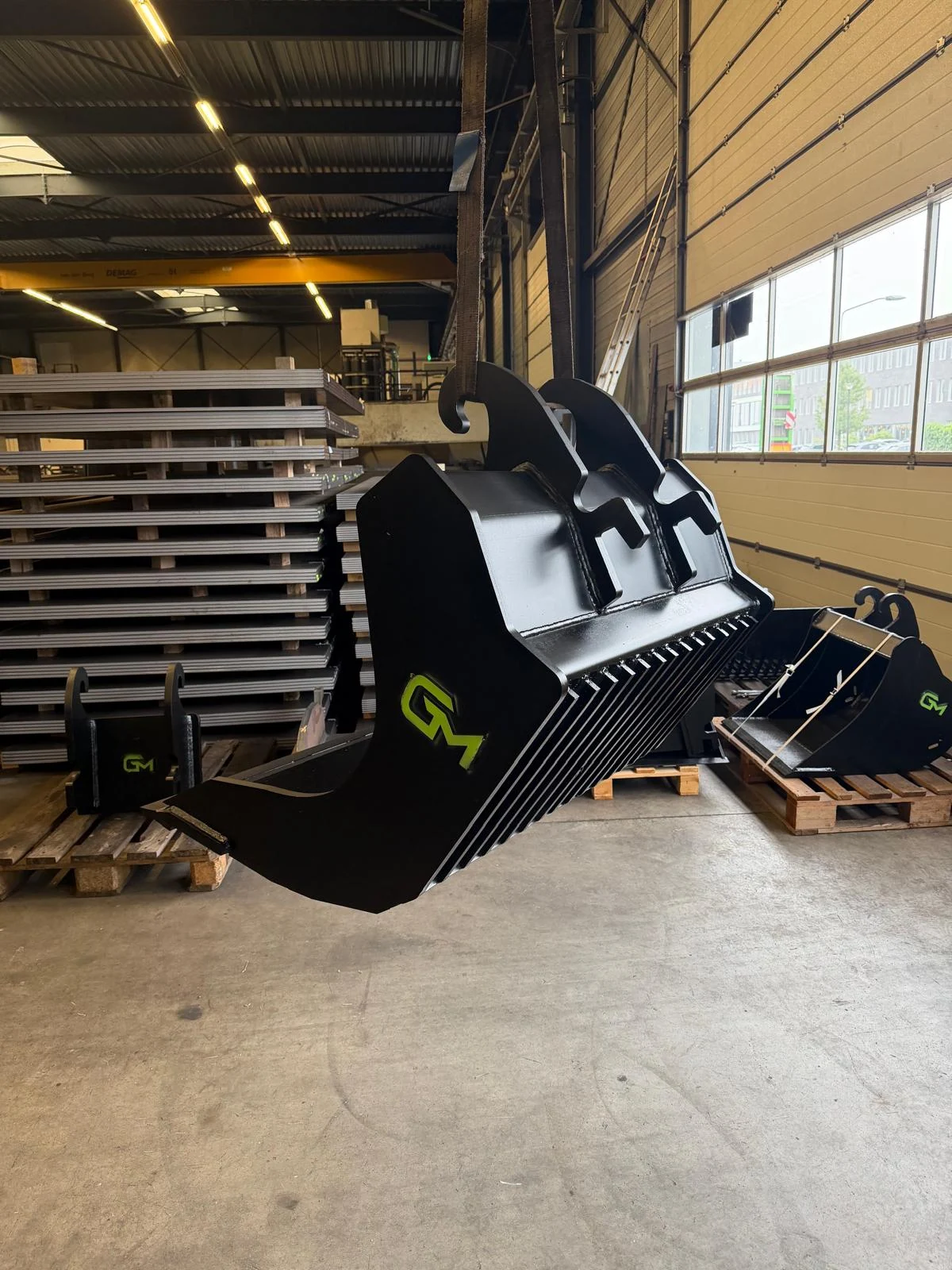 Zwarte GM puinbak met groen logo in onze werkplaats